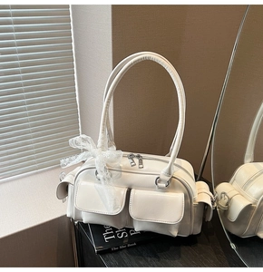 Detail of white PU leather Boston bag featuring front pockets and a delicate lace bow