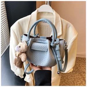 Détail de mini sac seau bleu avec pendentif ours et texture plissée élégante