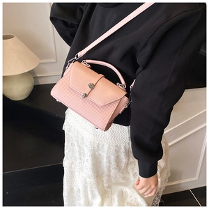 Vue détaillée du sac rose avec texture tressée et boucle métallique ronde de style rétro