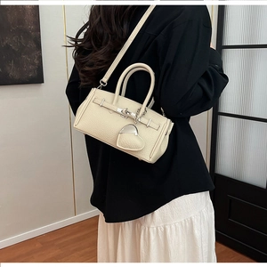 Dettaglio borsa in pelle color crema con ciondolo a cuore e tracolla rimovibile