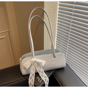 Close-up of light blue baguette bag with white lace bow and long leather shoulder straps