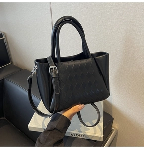 Detail view of black faux leather bucket bag featuring woven diamond texture and silver hardware