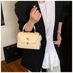 Détail du sac bandoulière tressé crème avec serrure cylindrique argentée et rabat cuir