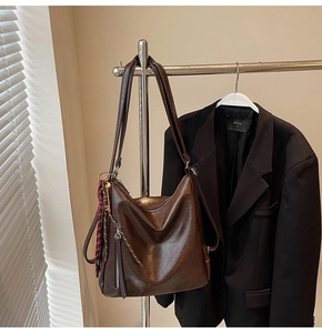Dettaglio della borsa tote in pelle cerata marrone con nappa e cerniera laterale