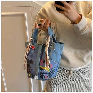 Mirror selfie showing blue denim bucket bag with heart prints and tennis racket charm