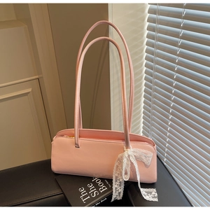 Detail of light pink rectangular underarm bag with a white lace bow charm on it