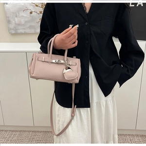 Dettaglio borsa in pelle rosa con serratura argento e ciondolo a forma di cuore