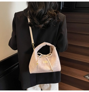 Detail of light pink crossbody bag with bow drawstring and gold metal hooks
