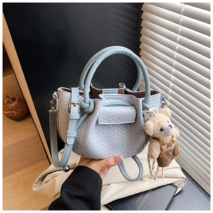 Détail du sac seau bleu clair avec texture plissée et charmant ourson en peluche