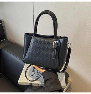 Detail of black quilted bucket bag featuring dual cylindrical handles and silver hardware