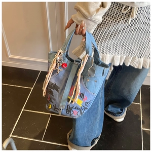 Detailed top view of denim bucket bag with graffiti prints and decorative charms