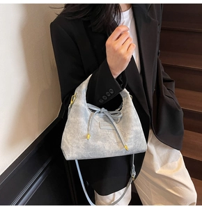 Detail of light blue crossbody dumpling bag with drawstring bow and metal buckle