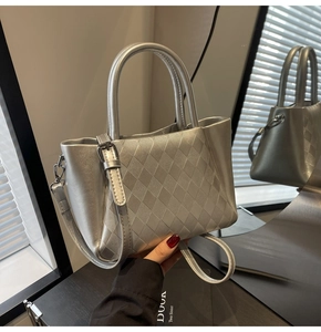 Detail of silver bucket bag showing textured rhombic pattern and metal strap buckle
