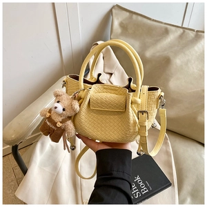 Détail du sac seau plissé jaune avec pendentif ours et texture en similicuir tissé