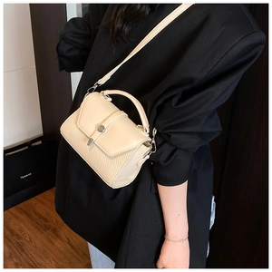 Sac à bandoulière beige tendance avec texture tissée et fermoir en métal sur modèle