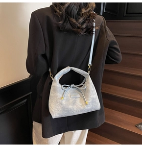 Detail of light blue denim tote bag with bow drawstring and metal caps on wooden stairs