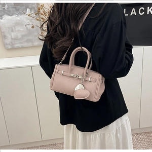 Dettaglio borsa in pelle litchi rosa con chiusura a scatto e ciondolo a forma di cuore