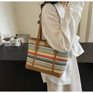 Detail of colorful striped woven tote bag with brown leather handles and brand tag