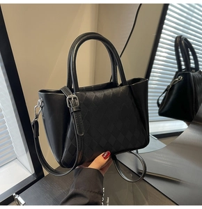 Detailed close-up of black quilted tote bag featuring silver hardware and a top handle