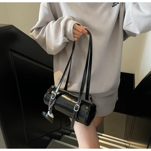 Detail of black glossy cylinder bag with silver heart charm and adjustable straps