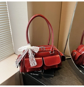 Detail view of dark red patent leather Boston bag featuring white lace bow and side pockets