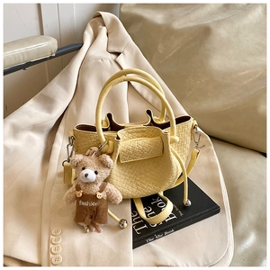 Détail du sac seau plissé jaune avec texture tissée et breloque ours mignonne