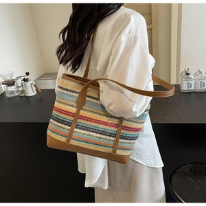 Detail of colorful woven straw tote bag with brown leather strap worn by a model