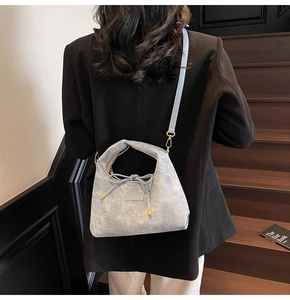 Detail of light gray crossbody bag with bow tie design and golden metal accents