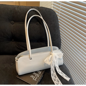 Detail of light blue baguette bag with lace bow accessory on a soft corduroy surface