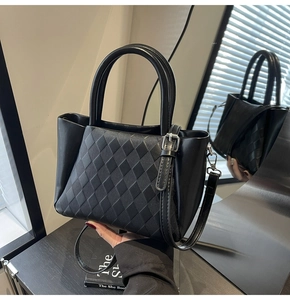 Detailed close-up of a black quilted tote bag with curved handles and a glossy mirror reflection