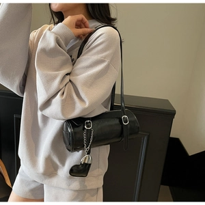 Detail of black cylinder bag in oily leather with silver buckle and heart charm