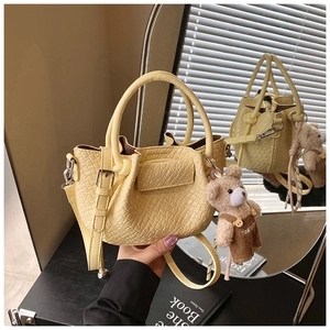 Détail du sac seau jaune motif croco avec un petit pendentif en ours en peluche