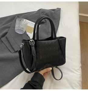 Detail of black quilted tote bag with silver hardware on a professional desk setup