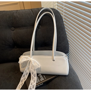 Detail of light blue pillow bag featuring lace bow decor on grey corduroy sofa