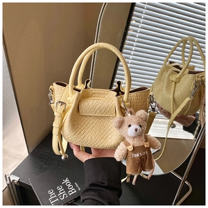 Détail du mini sac seau jaune avec bords ondulés et pendentif ours en peluche