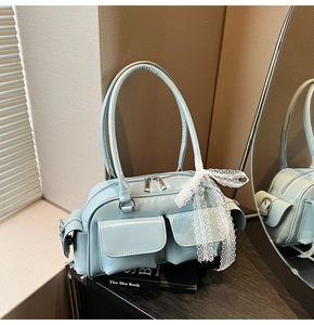 Detail of light blue patent leather Boston bag with functional front pockets and lace bow