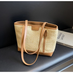 Detailed view of woven straw tote bag with brown leather straps and fashion logo patch