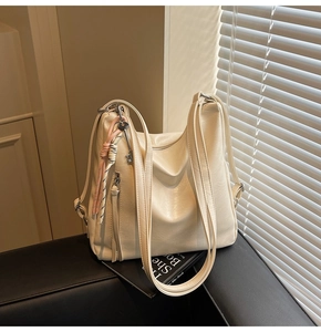 Dettaglio della borsa hobo in pelle PU bianco avorio con texture, tracolle e ciondoli