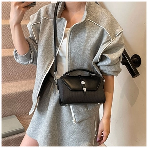 Détail du sac en cuir noir avec fermoir floral argenté présenté sur des escaliers