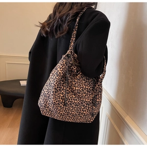 Détail d'un sac cabas léopard en toile porté à l'épaule sur un grand manteau noir