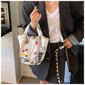 Detail of white canvas bucket bag with street art graffiti and vibrant colorful charms