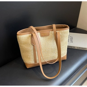 Detail of woven straw tote bag with brown leather straps and fashion label tag