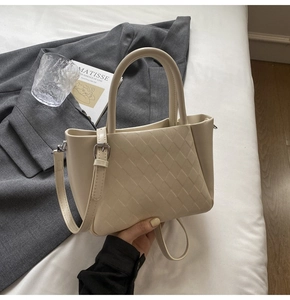 Detail of beige quilted tote bag featuring silver hardware and a minimalist leather texture