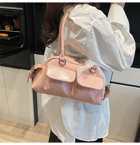Close-up of pale pink Boston bag with glossy finish and white lace bow detail