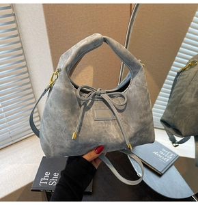 Macro shot of light blue denim texture bag featuring a bow detail and gold hardware