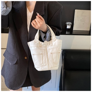 Detail of cream canvas bucket bag with contrast brown stitching and dual front pockets