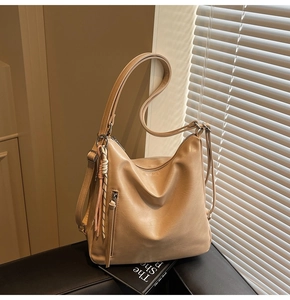 Dettaglio di uno zaino minimalista in similpelle beige con zip verticale e ciondolo a nappa