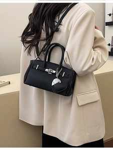 Borsa a mano in pelle nera con chiusura argento e ciondolo a cuore indossata da modella