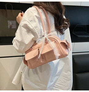 Detail of pink glossy leather Boston bag with front pockets and white lace bow accessory
