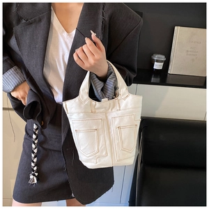 Detail of white canvas tote bag with contrast brown stitching and front pockets